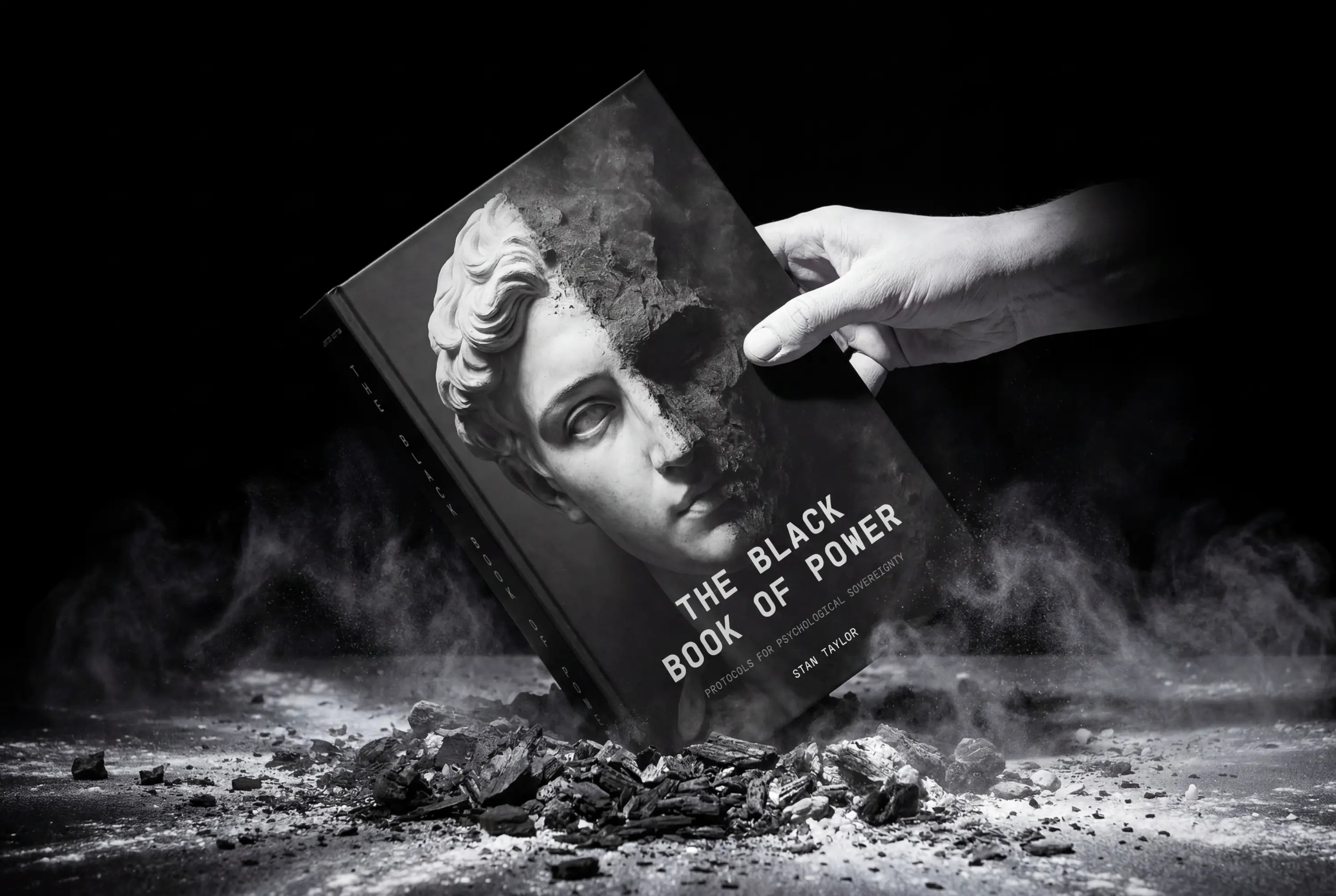 The Black Book of Power by Stan Taylor, marble-face cover rising from ash as a finger touches it