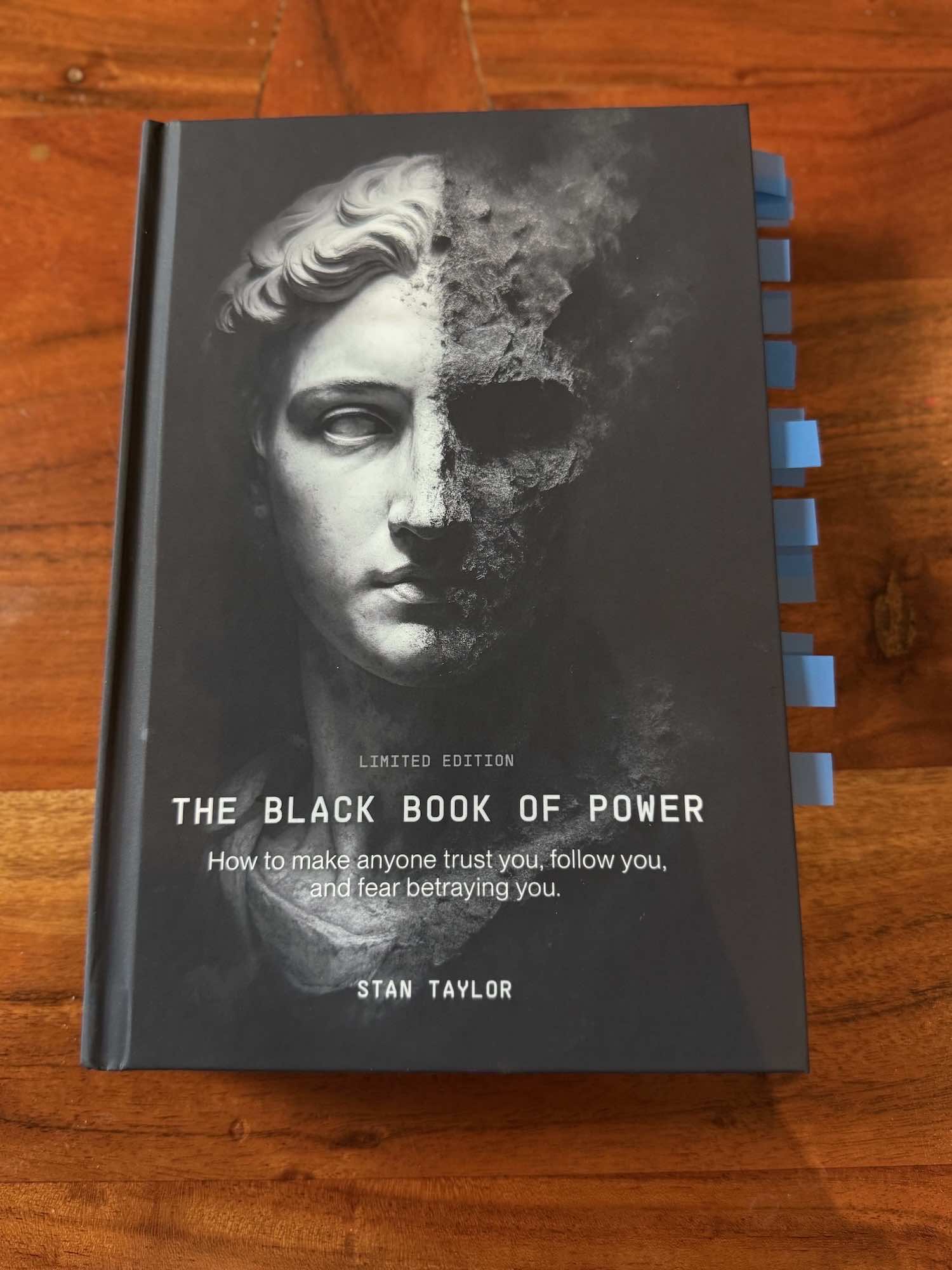 Book titled 'The Black Book of Power' by Stan Taylor on a wooden surface